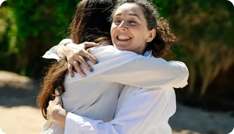there is a woman hugging another woman in a white shirt