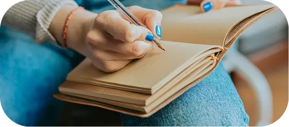 someone is writing on a book with a pen and a pencil