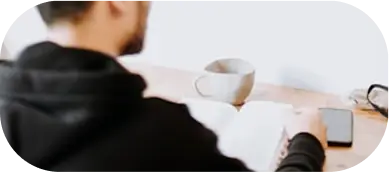 there is a man sitting at a desk with a laptop and a cup of coffee